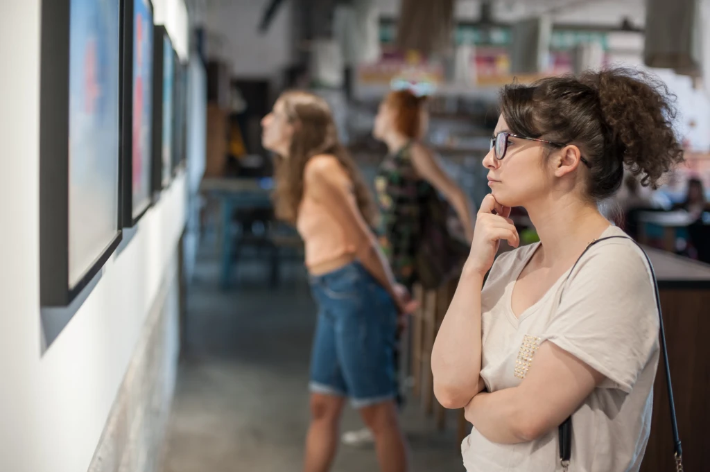 A person looking at a pictured frame on the wall