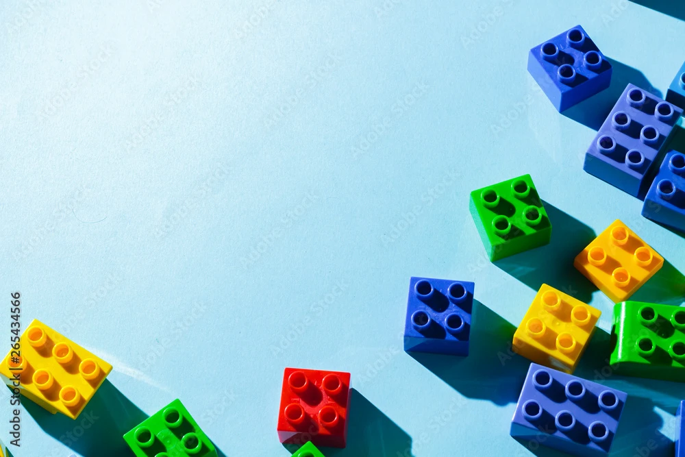 Multicolored details from the children's designer on a blue background. Flat lay, top view.
