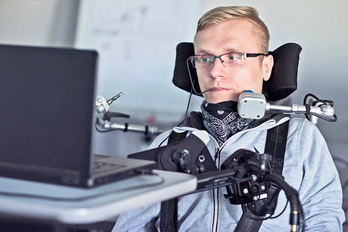 A physically disabled man using a laptop with assistive technology