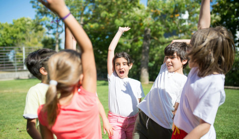 Five children raising their one hand in celebration, possibly to do a combined high five