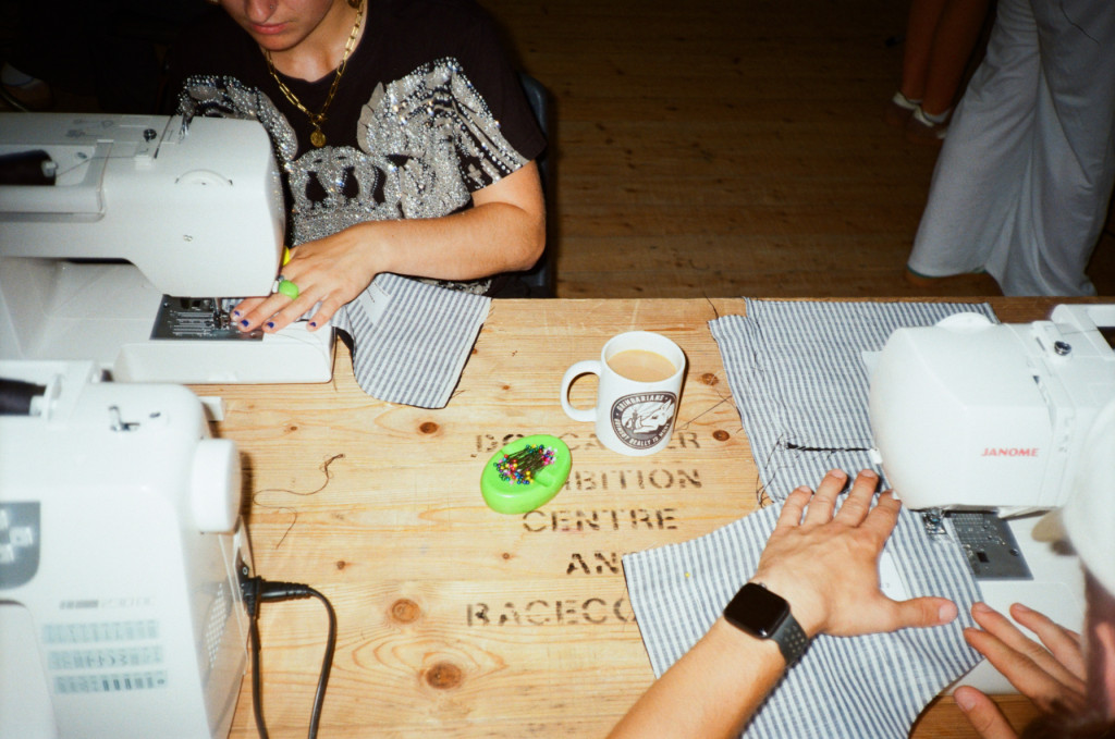 Photograph of people sewing, using sewing machines