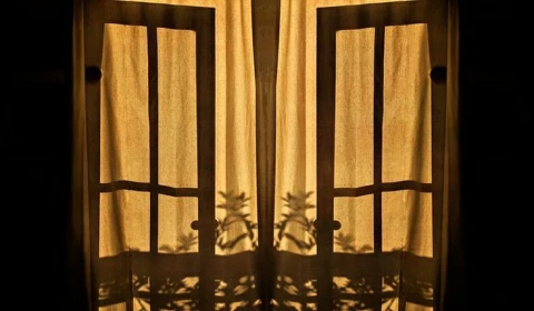 Windows seen from the outside, with golden light coming through the curtains.