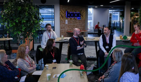 A group of people in smart casual business attire sat around a table, deep in conversation